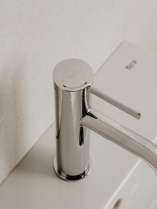 ekranna-snimka-2026-07-09-084935png - Мебели за баня и душкабини Close-up of a shiny chrome faucet with a horizontal lever, mounted on a white sink against a light wall.