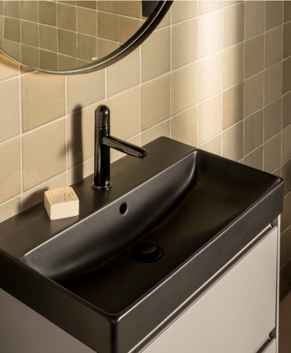 Екранна снимка 2026-07-26 172736 - Мебели за баня и душкабини Black bathroom sink with a sleek chrome faucet, a bar of soap on the counter, beige tiled wall, and part of a round mirror above.