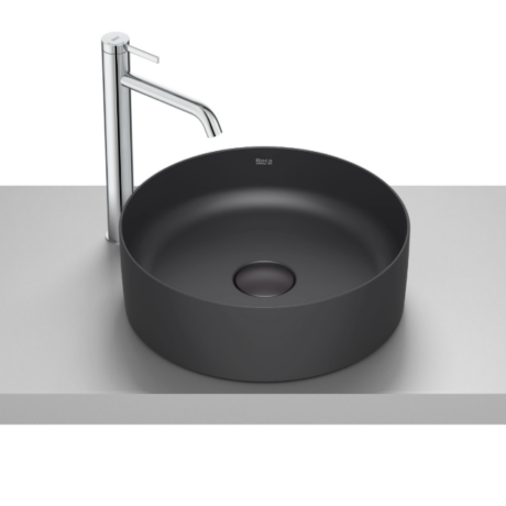 Round matte black vessel sink with a tall chrome faucet on a light gray countertop.