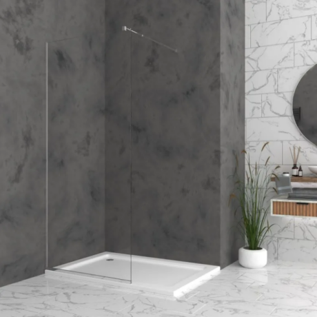 Modern bathroom shower with a glass panel, white tray, dark gray walls, and a marble floor; a plant sits by a marble-topped vanity with a round mirror nearby.