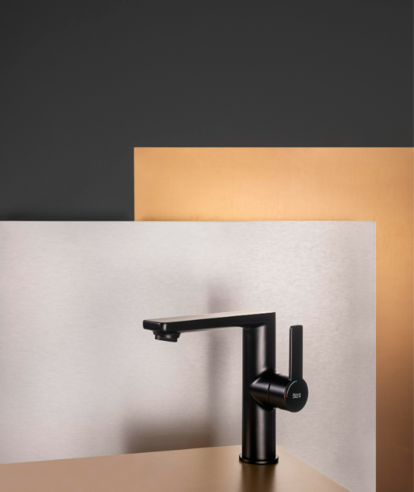 Екранна снимка 2026-08-01 091938 - Мебели за баня и душкабини Modern black kitchen faucet with single lever mounted on a beige countertop, against layered metallic panels in gray and copper tones.