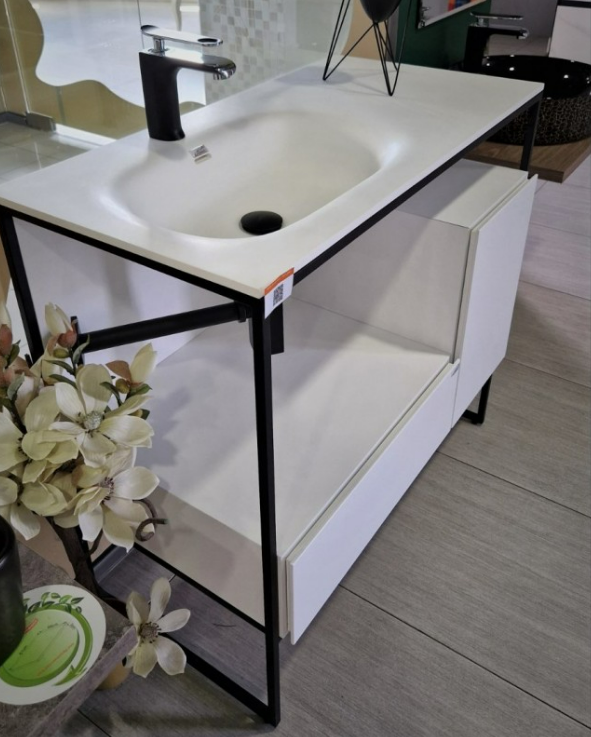 Екранна снимка 2026-08-04 075652 - Мебели за баня и душкабини White bathroom vanity with an integrated sink and black faucet on a black metal frame, open lower shelf, in-store showroom setting