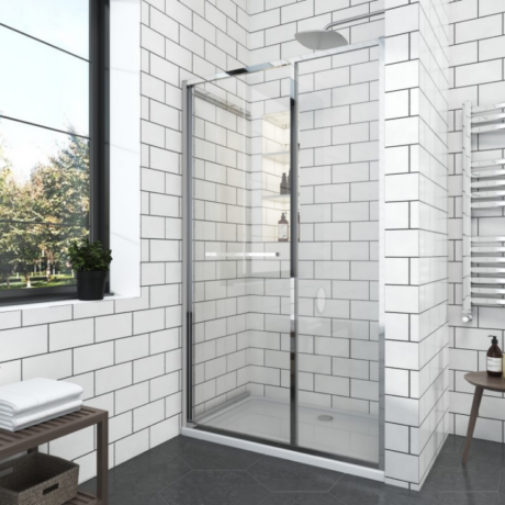 Modern bathroom with a glass sliding shower enclosure, white subway tile walls, and a window with a potted plant.
