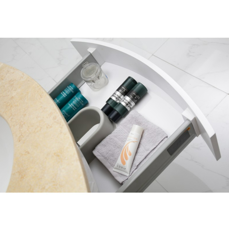 Open bathroom vanity drawer with organized toiletries: teal and green bottles, a small jar, a white tube, a folded towel, and a gray cup on a marble countertop.