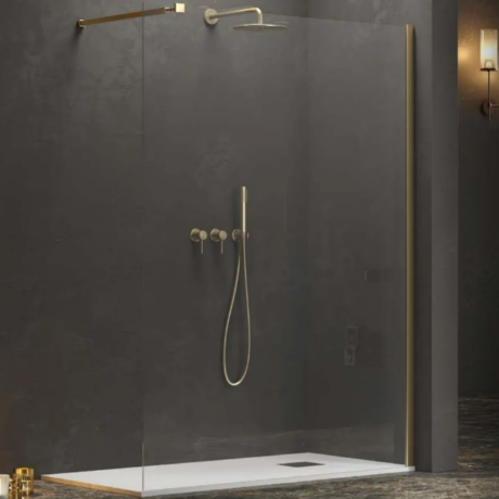 Modern glass shower enclosure with brass fixtures, handheld shower and wall-mounted controls on dark slate walls.